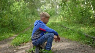 Demiryolu üzerinde oturan yalnız bir genç çocuk