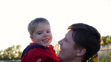 Genç bir baba çocuğunu onun kollarında tutar. Hassasiyet ve sevgili babam benimsemesi. Açık hava etkinlikleri