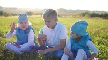 Çocuklar parkta çim üzerinde durur. Gülmek, sarılmak ve öpmek hava. Çocuk tatil açık havada