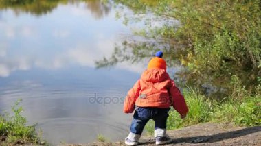 Bir çocuk taş atmak ve havuz kıyısında duruyor. Temiz havada yürüyüşler