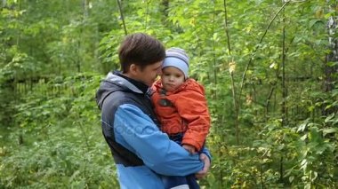 Genç bir baba çocuğunu onun kollarında tutar. Hassasiyet ve sevgili babam benimsemesi. Açık hava etkinlikleri