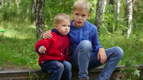 Un adolescent solitaire et son jeune frère assis sur la voie ferrée — Video