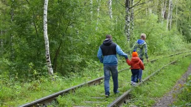 En tonårig pojke och hans yngre bror går med min far på järnvägsspåren. Farligt spel och underhållning — Stockvideo