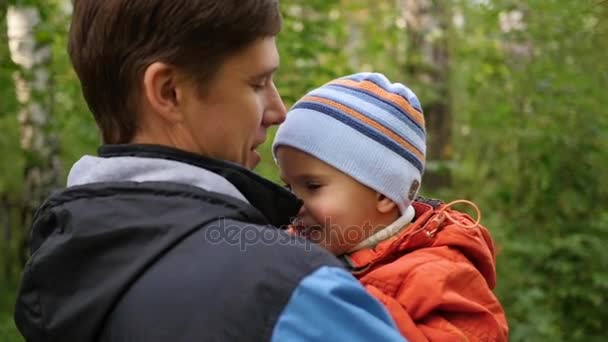 En ung fader håller sitt barn i famnen. Ömhet och omfamning av den älskade far. Utomhusaktiviteter — Stockvideo