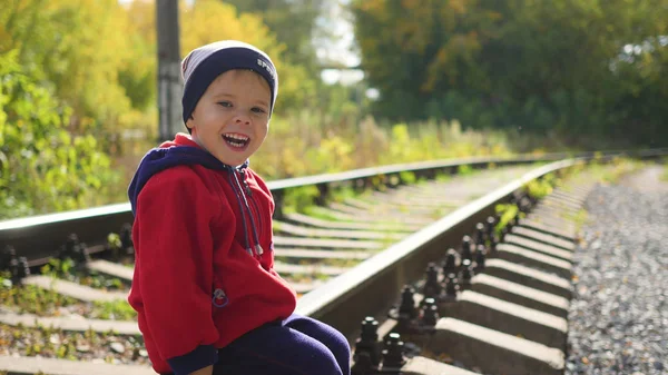 Un ragazzo solitario seduto sui binari della ferrovia. Giochi pericolosi e intrattenimento — Foto Stock