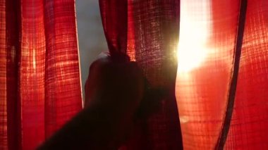 Kız kırmızı perdeler açılır ve elleri ile güneş ışınları ile oynadı. El portre