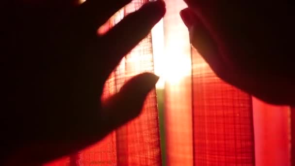 The girl opens red curtains and played with his hands through the suns rays. Hand closeup — Stock Video