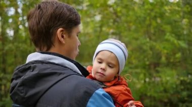 Genç bir baba çocuğunu onun kollarında tutar. Hassasiyet ve sevgili babam benimsemesi. Açık hava etkinlikleri