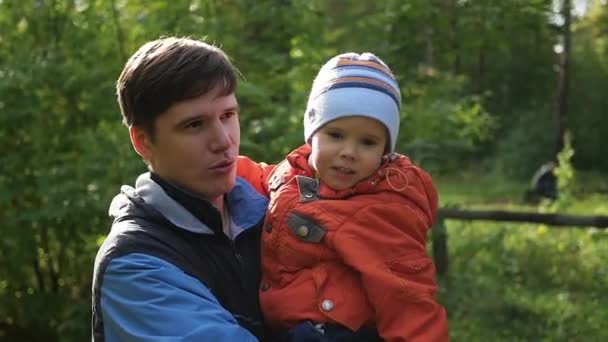 젊은 아버지는 그의 팔에 그의 아이 보유 하고있다. 부드러움과 사랑 하는 아버지의 포옹 야외 활동 — 비디오