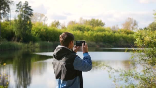 Jonge vent neemt foto's van de herfst landschap op de telefoon. — Stockvideo