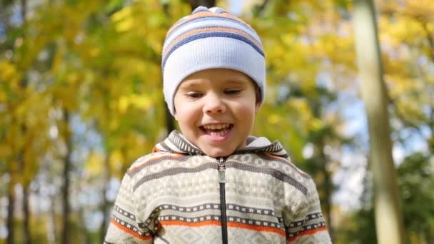 Ребенок в осеннем парке веселится, играет и смеется, гуляет на свежем воздухе — стоковое видео