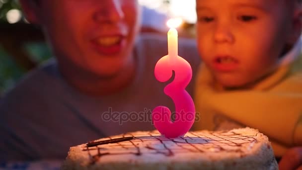Ребенок раздувает свечу на торте в свой день рождения с отцом — стоковое видео