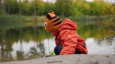 Gölün kıyısında oynayan bir çocuk. Temiz havada yürüyüşler. Sonbahar manzara. Gökyüzü ve Gölü nün su ağaçlarda yansımasıdır. Çok güzel manzaralı bir yer
