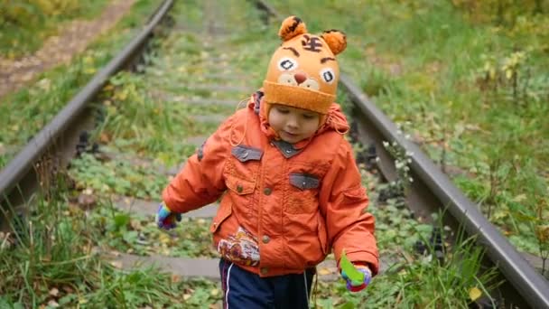 Ένα μοναχικό αγόρι με τα πόδια για τις σιδηροδρομικές γραμμές. Επικίνδυνα παιχνίδια και την ψυχαγωγία. Ημέρα του φθινοπώρου — Αρχείο Βίντεο
