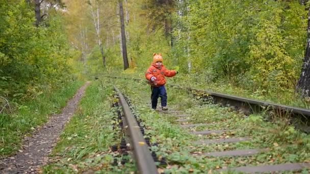 Demiryolu üzerinde yürüyen yalnız bir çocuk. Tehlikeli Oyunlar ve eğlence. Sonbahar günü — Stok video