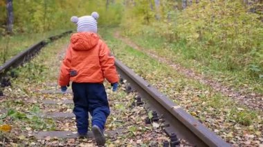 Demiryolu üzerinde yürüyen yalnız bir çocuk. Tehlikeli Oyunlar ve eğlence. Sonbahar günü