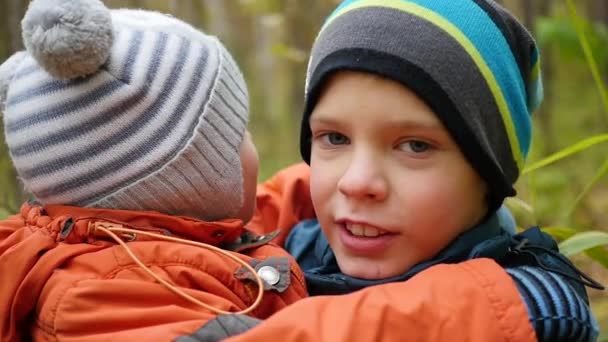 Boy hugs and kisses his younger brother and holding him in my arms — Stock Video