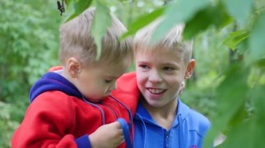 Çocuk küçük kardeşi hugs ve onun kollarını tutar. Yaz Park