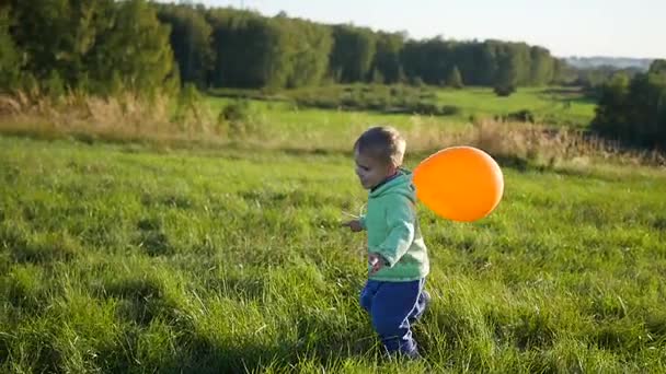 Chico feliz corriendo con un globo en el parque. Paseo y entretenimiento al aire libre — Vídeos de Stock