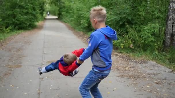 Zpomalený pohyb. Nejstarší dítě whirlpool svého smějícího se bratra. Zábava pod širým nebem — Stock video