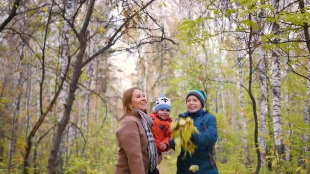 Ragazza con bambini in autunno Park lancia foglie gialle. Famiglia felice che ride e sorride — Video Stock