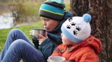 çim ve İçecek sıcak çay üzerinde oturan sonbahar Park çocuklarda temiz havada yürüyüş