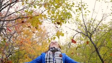 Kız sonbaharın sarı yaprakları Park atar. Gülerek ve gülümseyerek mutlu kız