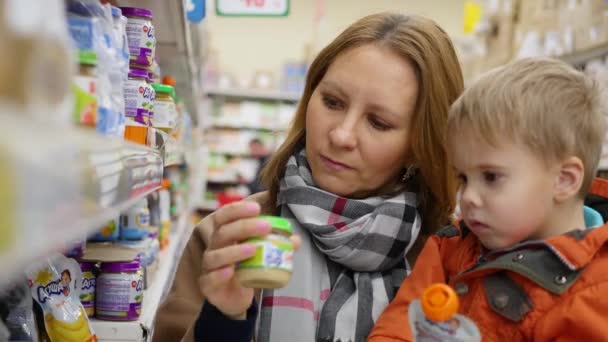 NOVOSIBIRSK, RUSIA - 7 de octubre de 2017: una madre con un niño en la tienda eligiendo comida para bebés — Vídeos de Stock