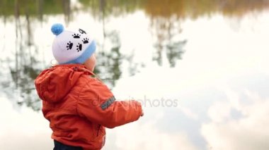 Bir çocuk taş atmak ve havuz kıyısında duruyor. Temiz havada yürüyüşler