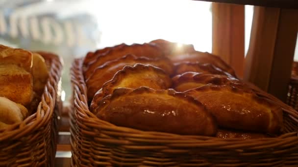 Pâtisseries fraîches dans un panier en vitrine, dans le magasin. Rayons de soleil à travers les pâtisseries — Video
