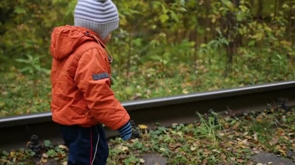 鉄道の線路の上を歩く孤独な少年。危険なゲームとエンターテイメント。秋の日 — ストック動画