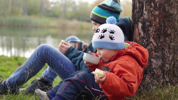 V podzimní Park děti, které sedí na trávníku a pít horký čaj procházka na čerstvém vzduchu — Stock video