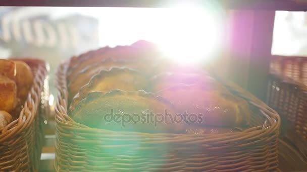 Pâtisseries fraîches dans un panier en vitrine, dans le magasin. Rayons de soleil à travers les pâtisseries — Video