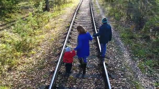 Demiryolu üzerinde yürüyen iki çocuklu genç bir kız. Sonbaharda açık havada yürüyüş. — Stok video