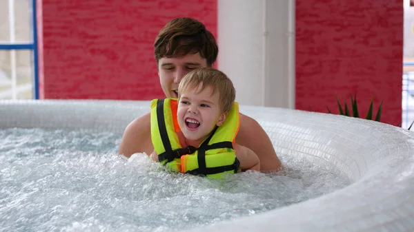 A young father with a child swims in the Spa pool. Relaxation and fun in the pool