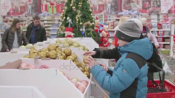 Venta navideña de juguetes y árboles de Navidad hasta Navidad. La gente en el supermercado está de compras antes del año nuevo. Regalos de Navidad para seres queridos — Vídeos de Stock