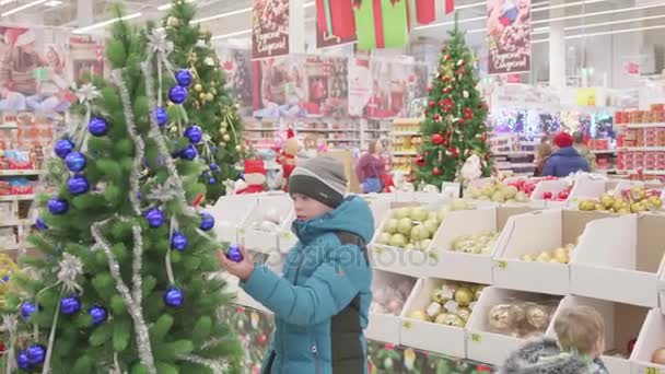 Venta navideña de juguetes y árboles de Navidad hasta Navidad. La gente en el supermercado está de compras antes del año nuevo. Regalos de Navidad para seres queridos — Vídeos de Stock