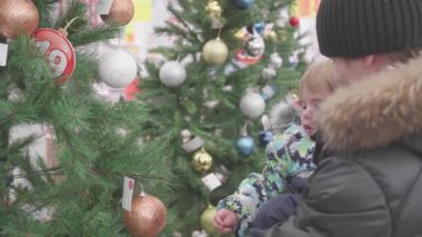 Novosibirsk, Rusya Federasyonu - Kasım 25,2017: baba ve oğul seçin bir Noel ağacı içinde belgili tanımlık stok. Oyuncaklar ve Noel ağaçları xmas kadar satışı. Sevdikleriniz için Noel hediyeleri