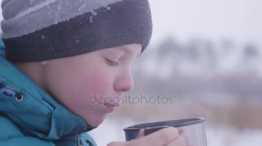 Çocuk çay kışın dışarıda parkta içiyor