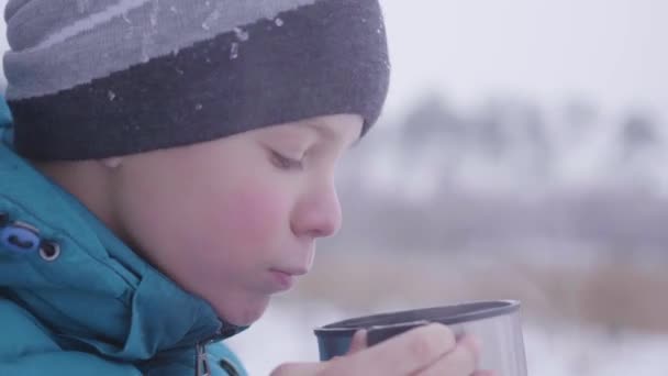 Ребенок пьет чай на улице зимой в парке — стоковое видео