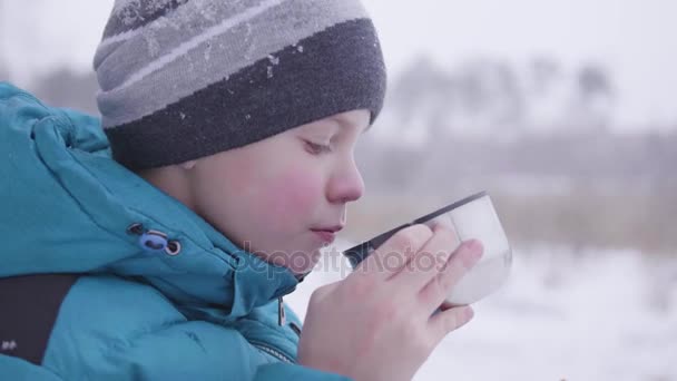 Το παιδί πόσιμο τσάι το χειμώνα σε εξωτερικούς χώρους στο πάρκο — Αρχείο Βίντεο