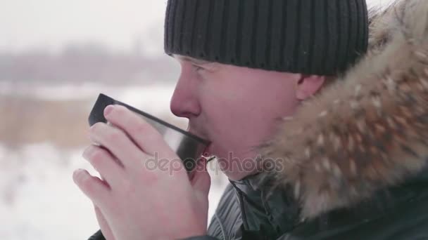 Mannen dricker varmt te på vintern utomhus i parken. Hälsosam livsstil, promenader utomhus — Stockvideo