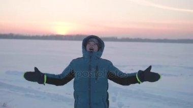 Bir çocuk kış havada oynar, çalışır, kar üstüne atar. Güzel gün batımı. Etkin açık spor
