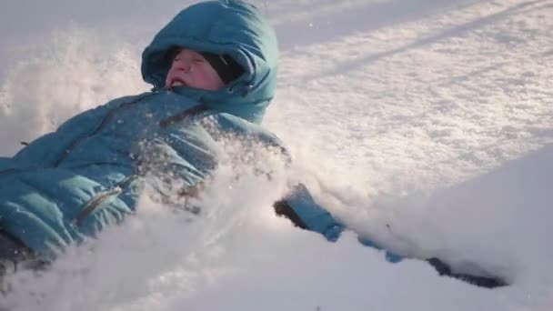 Barn faller snön i slow motion. Aktiv sport utomhus. Solig vinterdag — Stockvideo