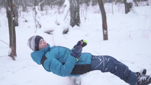 Ребенок падает в снег в замедленной съемке. Активный спорт на открытом воздухе. Зимний солнечный день — стоковое видео
