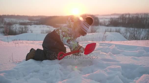 Ein kleines Kind, das im Winterpark mit Schnee spielt. sonniger Wintertag. Spiel und Spaß an der frischen Luft. — Stockvideo