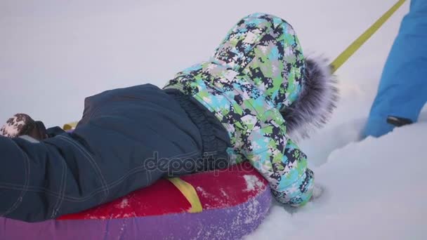 Un niño feliz monta en tubo de nieve en una cámara lenta de nieve. nieve invierno paisaje. deportes al aire libre — Vídeos de Stock