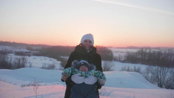 Молода дівчина з дитиною, граючи в зимовий період Park.Walks на свіжому повітрі. Захід сонця — стокове відео