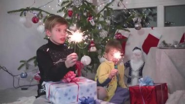 iki çocuk maytap yaktı. Bokeh ışıkları ve çelenk Noel ağacının arka planda