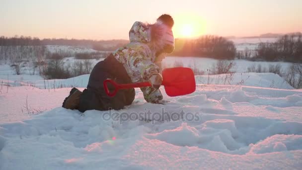 Ein kleines Kind, das im Winterpark mit Schnee spielt. sonniger Wintertag. Spiel und Spaß an der frischen Luft. — Stockvideo